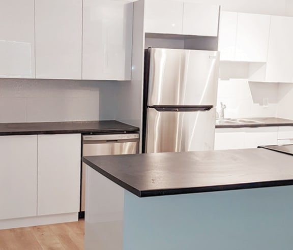 A kitchen with a stainless steel refrigerator and white cabinets.