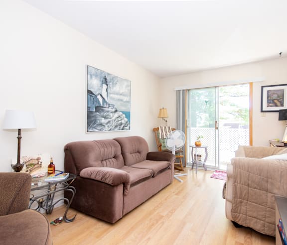 A living room with a brown couch and a painting on the wall.