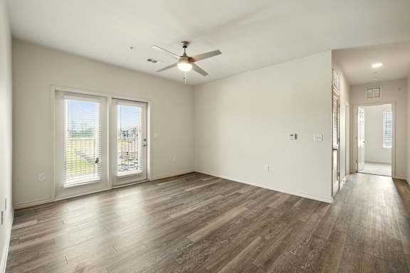 A spacious room with a ceiling fan and sliding glass doors.