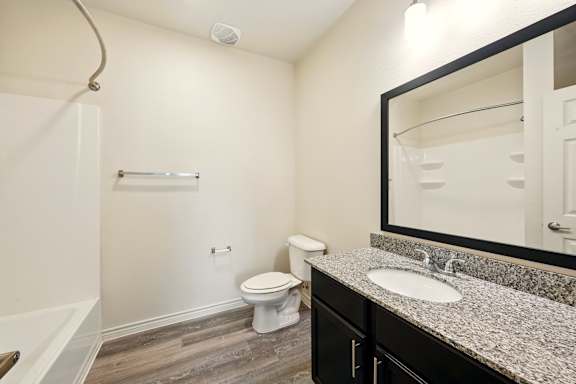 A bathroom with a toilet, sink, and mirror.