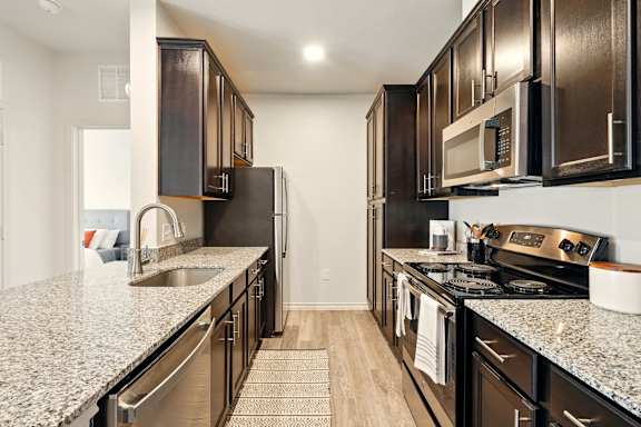 A kitchen with dark wood cabinets and granite countertops.