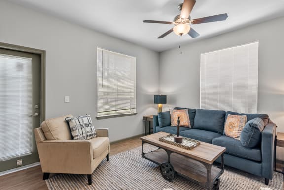 a living room with a couch and a chair and a ceiling fan