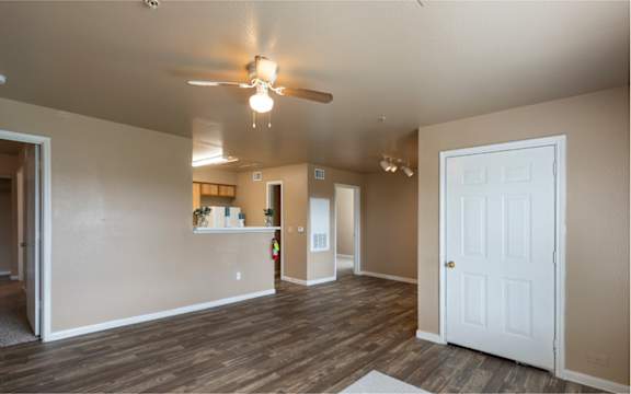 A room with a ceiling fan and wooden floors.