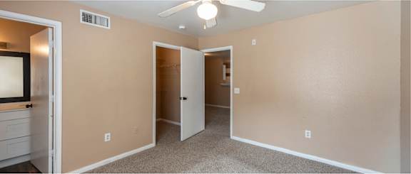 A room with a ceiling fan and a mirror on the wall.