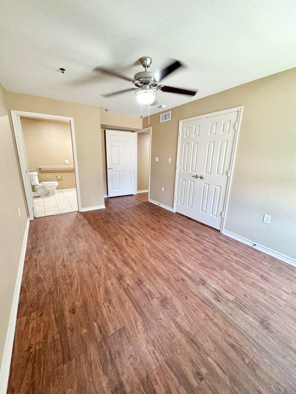 A room with a ceiling fan and wooden flooring.
