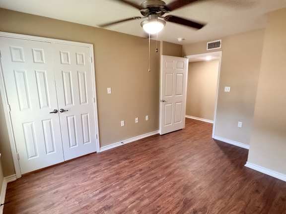 A room with a ceiling fan and wooden flooring.