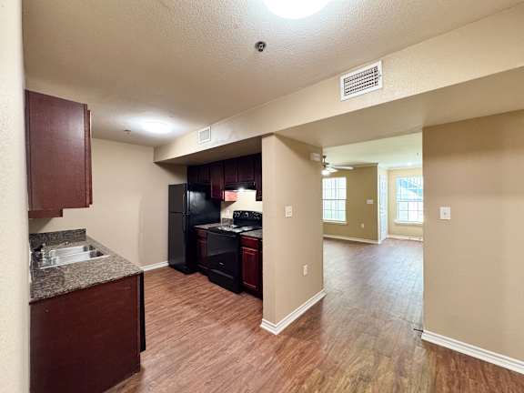 A kitchen with dark wood cabinets and a black refrigerator.