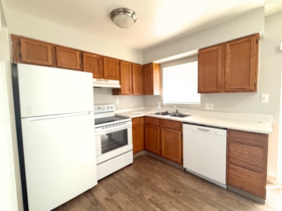 A kitchen with white appliances and wooden cabinets at Mountain Terrace Apartments , Colorado, 80031