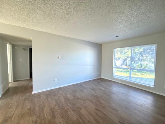 A room at Mountain Terrace Apartments  with wooden floors and a window showing a view of a fence and trees at Mountain Terrace Apartments , Westminster, CO