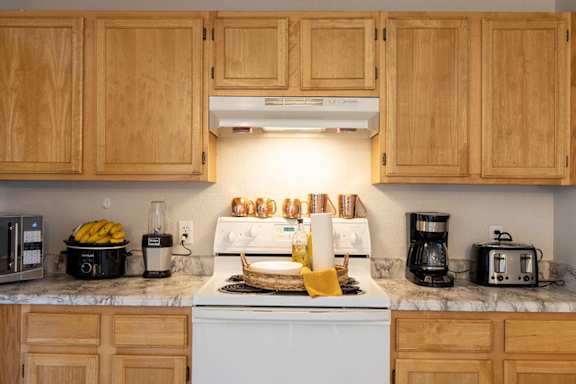 A kitchen with a stove top oven and a toaster. at Meeker Commons Apartments , Greeley, CO