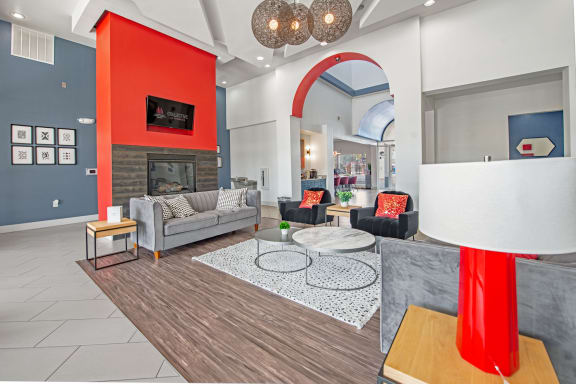 a living room with gray couches and a red accent wall