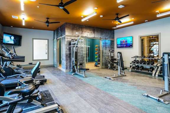 A gym with treadmills, exercise bikes, and a television.