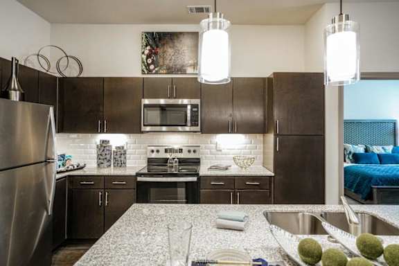 A modern kitchen with a stainless steel refrigerator and a granite countertop.