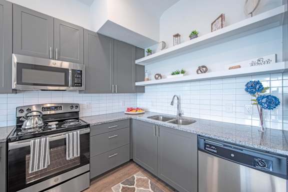 a kitchen with gray cabinets and white countertops  at Presidium Pecan District, Pflugerville