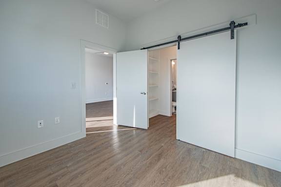 a bedroom with white walls and a wooden floor  at Presidium Pecan District, Pflugerville, Texas