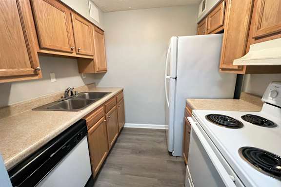 A kitchen with a white fridge, black stove, and wooden cabinets.