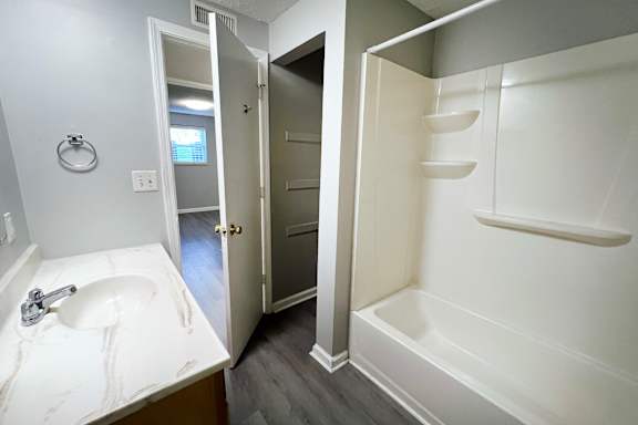 A bathroom with a sink, mirror, and bathtub.