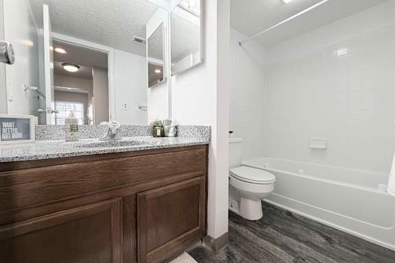 A bathroom with a wooden vanity and a white toilet.