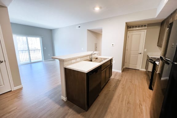 an empty kitchen and living room with wood flooring and a large window  at Brookfield Village Apartments, Grove City