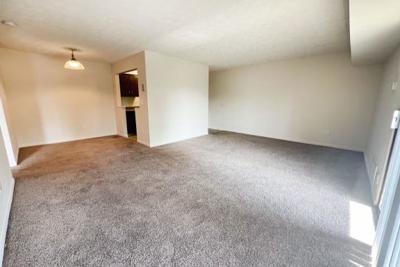 an empty living room with carpet and white walls at Four Worlds Apartments, Cincinnati
