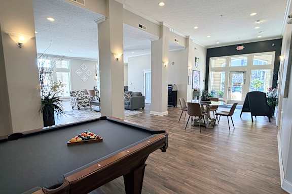 A pool table is in the middle of a room with a dining table and chairs.