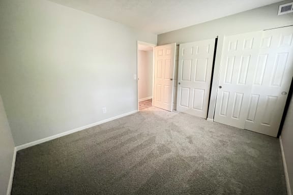 an empty bedroom with white doors and carpet at Crown Crossing Apartments, Amelia, OH