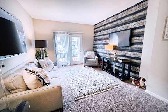 A living room with a couch, a rug, a TV, and a wooden wall.