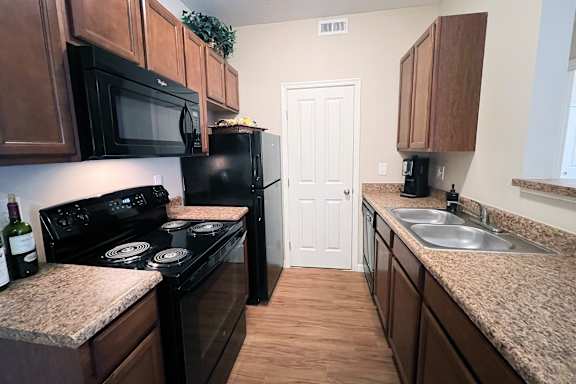 A kitchen with black appliances and brown cabinets.