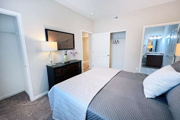 A bedroom with a large bed and a dresser with a mirror above it.