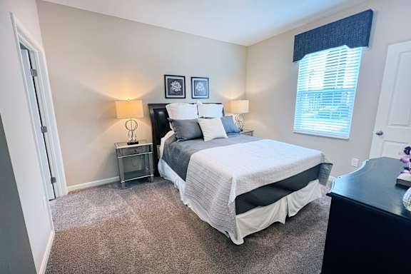A bedroom with a bed, nightstands, and two wall lamps.