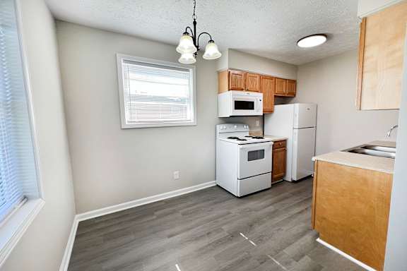A kitchen with white appliances and wooden cabinets.