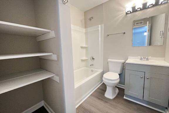 A white toilet sits in a bathroom next to a sink and a bathtub.