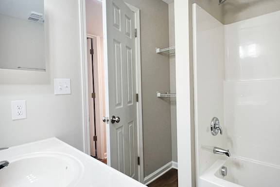 A white bathroom with a white tub and a white sink.