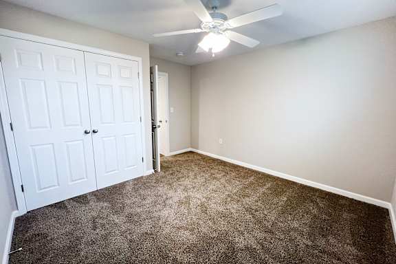 A room with a ceiling fan and carpeted floor.