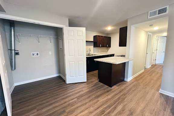 A kitchen with a white door and a wooden floor.