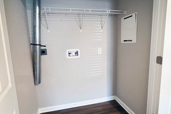A white closet with a shelf and a white door.