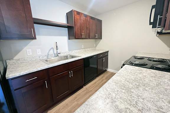 A kitchen with dark brown cabinets and a white marble countertop.