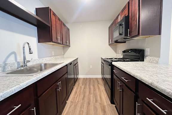 A kitchen with dark wood cabinets and a granite countertop.