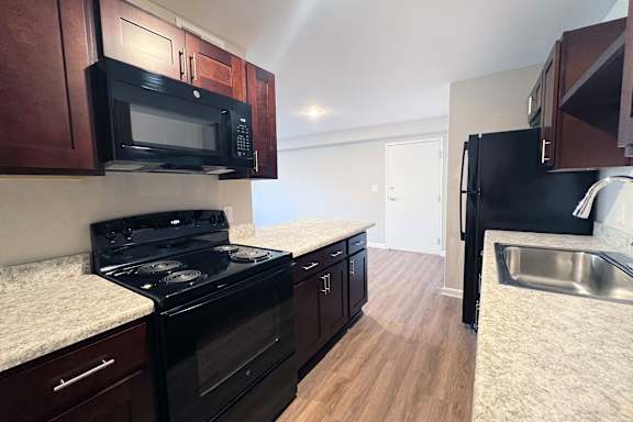 A kitchen with black appliances and wooden cabinets.