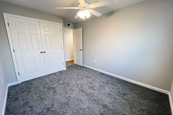 A room with a ceiling fan and carpeted floor.