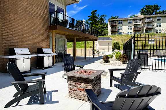 A patio with black chairs and a fire pit.