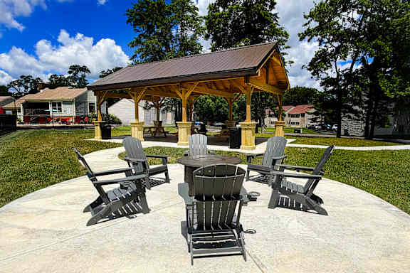 A gazebo with four chairs and a table is surrounded by trees.