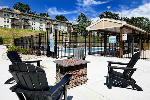A black chair is in front of a fire pit and a gazebo.