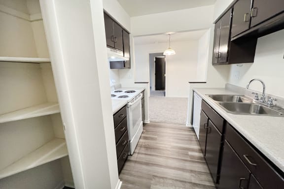 an empty kitchen with black cabinets and a white stove and sink at Four Worlds Apartments, Cincinnati, Ohio