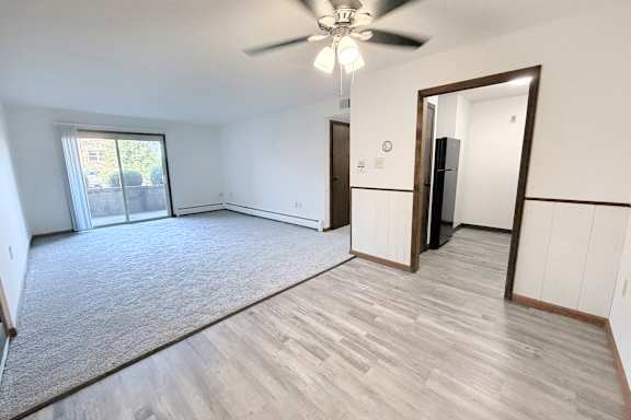 A room with a ceiling fan and a door leading to another room.