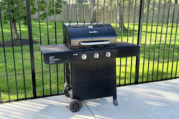 A charcoal grill is on a patio.