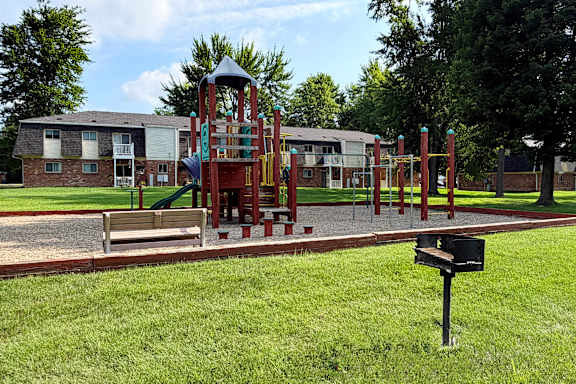 A playground with a slide and a swing set in front of a building.