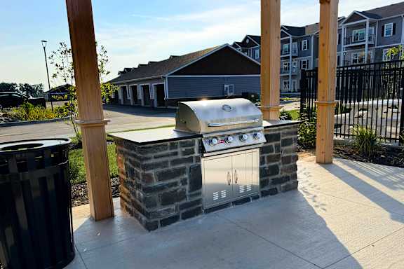 A BBQ grill is built into a stone structure in a residential area.