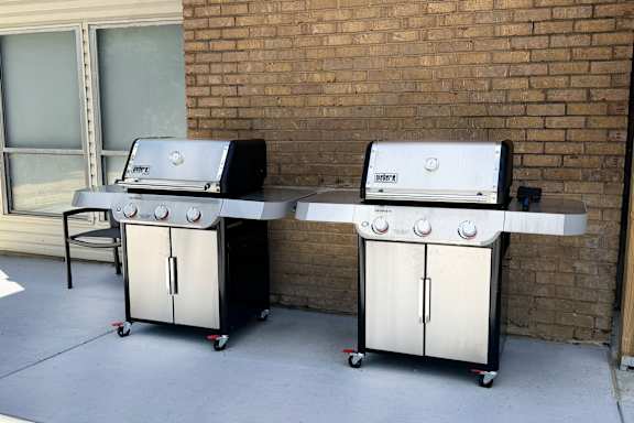 Two gas grills are on a patio.