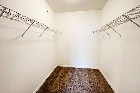 A white hallway with a brown carpet and metal racks on the wall.